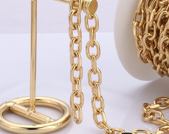 Könnte beinhalten: Eine goldene Kettenkette mit einem Karabinerverschluss. Die Kette besteht aus ovalen Gliedern und wird auf einem goldenen Ständer präsentiert.