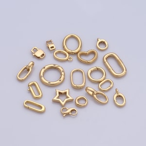 Puede incluir: Surtido de hallazgos de joyería de metal dorado, incluyendo cierres de langosta, anillos de salto y cierres de palanca. Los hallazgos están dispuestos sobre una superficie blanca.