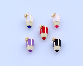 Può includere: Cinque ciondoli a forma di matita colorata con dettagli dorati. Ogni ciondolo presenta un colore diverso per la punta e la parte superiore della matita, tra cui bianco, rosso, viola, nero e rosa. I ciondoli sono su uno sfondo azzurro.