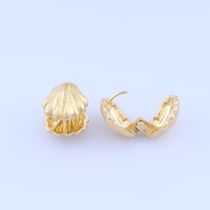 May include: Two gold-coloured seashell-shaped earrings. One earring is closed, and the other is open, revealing the clasp. The earrings have a detailed, textured surface, and are set against a white background.