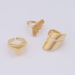 Puede incluir: Tres anillos dorados con diseños geométricos únicos. Los anillos son de metal y tienen un acabado brillante.