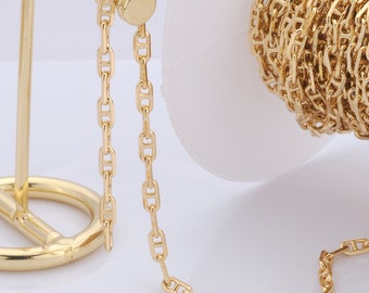 Könnte beinhalten: Eine goldfarbene Metallkette mit einem Ankerketten-Design. Die Kette wird auf einem goldfarbenen Metallständer und einer Spule präsentiert.