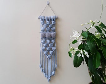 Small narrow blue macrame wall hanging with grey pom poms. Handmade mini pom pom wall decor. Modern vertical yarn home decor.