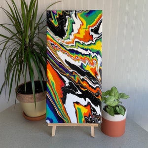 May include: Abstract painting on canvas with a colorful, swirling design in shades of black, white, green, yellow, orange, purple, and blue.
