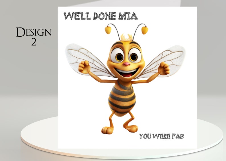 Pu&ograve; includere: Un biglietto di auguri con un'illustrazione di un'ape dei cartoni animati. L'ape &egrave; gialla e nera con le braccia tese e un volto sorridente. Il testo sul biglietto recita "WELL DONE MIA" e "YOU WERE FAB". Il biglietto &egrave; etichettato "DESIGN 2".