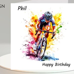 May include: A white greeting card with a watercolor painting of a cyclist in action. The cyclist is wearing a helmet and cycling gear. The card has the text "Design 4", "Phil", and "Happy Birthday".