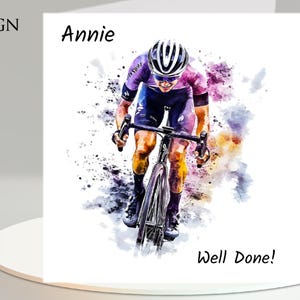 May include: A watercolor-style greeting card featuring a cyclist in action, wearing a helmet and cycling gear. The card includes the text "Design 2", "Annie", and "Well Done!" in black font. The background has colorful paint splatters.