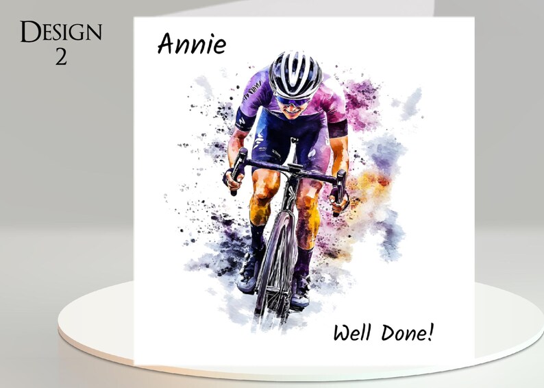 May include: A watercolor-style greeting card featuring a cyclist in action, wearing a helmet and cycling gear. The card includes the text "Design 2", "Annie", and "Well Done!" in black font. The background has colorful paint splatters.