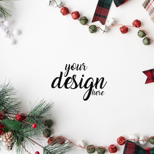 May include: A white background with a red and green plaid ribbon, red and green jingle bells, and a pine sprig with red berries. The text "your design here" is in the center of the image.