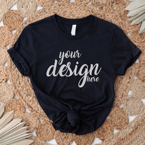 Pu&ograve; includere: Maglietta nera con il testo "your design here" su uno sfondo tessuto.