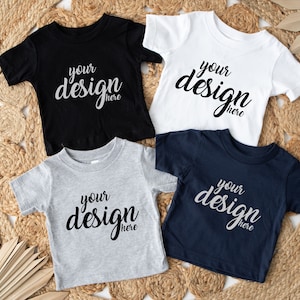 May include: Four short-sleeved t-shirts in black, white, grey, and navy blue. Each shirt has the text "your design here" printed on the front.