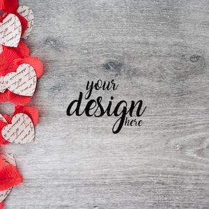 May include: Red and white heart-shaped paper with handwritten text on a gray wood background. The text "your design here" is written in black cursive.