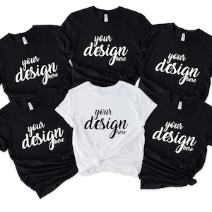 May include: Five t-shirts, two black and three white, with the text "your design here" printed on the front in a white cursive font.