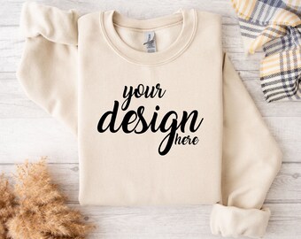 May include: A beige sweatshirt with the text "your design here" printed in black on the front.