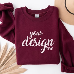 May include: A maroon sweatshirt with the text "your design here" printed in white on the front.