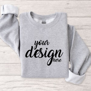 Può includere: Una felpa grigia con la scritta "your design here" stampata sul davanti.