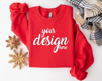 May include: Red sweatshirt with the text "your design here" printed on the front. The sweatshirt is laid flat on a white surface with two gold star ornaments.
