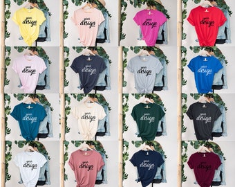 May include: A collection of 16 blank t-shirts in various colors, including yellow, pink, red, blue, gray, teal, white, beige, green, navy, and maroon. Each shirt is hanging on a hanger with a wooden dowel and has the text "your design" printed on the front.