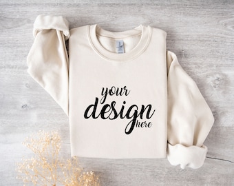 May include: A cream colored sweatshirt with the text "your design here" printed in black on the front.