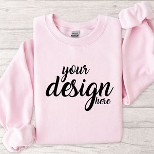 May include: A pink sweatshirt with the text "your design here" printed in black.