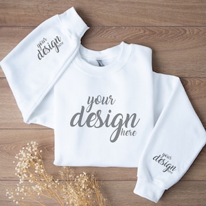 May include: White sweatshirt with long sleeves and a crew neck. The sweatshirt has the text "your design here" printed on the front and both sleeves.