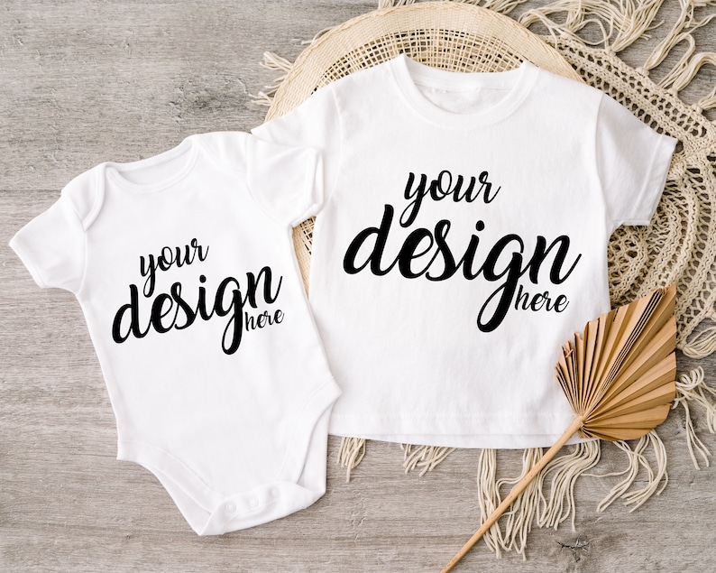 May include: Two white baby onesies with short sleeves. The onesies have the text "your design here" printed in black on the front.