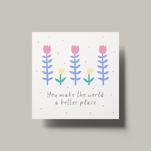 May include: A white card with a pink, blue, and yellow flower illustration. The card has the text "You make the world a better place."