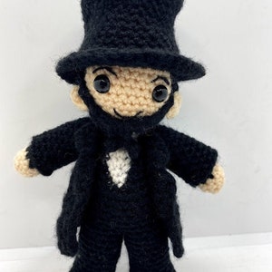 Puede incluir: Muñeca de ganchillo hecha a mano de Abraham Lincoln, con sombrero de copa negro, abrigo y pantalones. La muñeca tiene una cara bronceada, barba negra y ojos negros grandes. Un artículo único, hecho a mano.