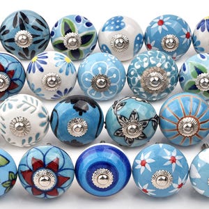Assorted hand-painted ceramic knobs with blue and turquoise floral motifs for kitchen décor and knob cupboards.