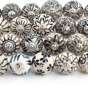 May include: A collection of 20 ceramic drawer knobs with black and white floral patterns. The knobs are round and have a slightly raised design.