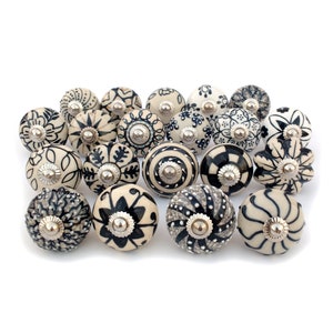 May include: A collection of 18 ceramic drawer knobs with black and white floral patterns. The knobs have a silver metal base.