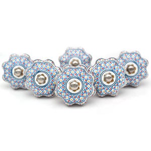 May include: Six blue and white ceramic knobs with a floral pattern and gold accents. The knobs have a scalloped edge and a silver centre.