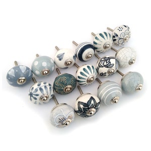 Könnte beinhalten: Ein Set mit 15 Keramik-Schubladengriffen in verschiedenen Blautönen und Grüntönen mit weißen und goldenen Akzenten. Die Griffe haben verschiedene Muster, darunter florale, geometrische und abstrakte Designs.