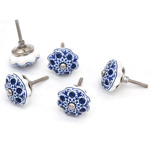 May include: A collection of five white and blue ceramic cabinet knobs. The knobs feature a floral design in blue against a white background. Each knob has a silver-colored metal screw for attachment.