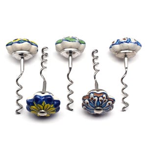 May include: Set of five colorful ceramic bottle openers with a floral design. Each opener has a silver metal corkscrew.