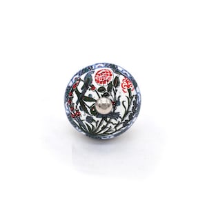 May include: A round ceramic cabinet knob with a floral and bird design. The knob features red, green, and blue accents on a white background. The knob has a silver metal screw.