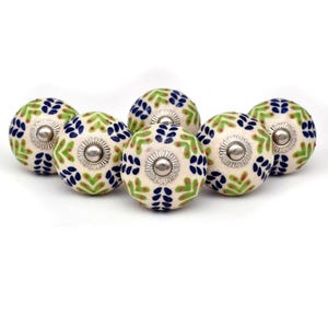 Peut inclure: Ensemble de six boutons de meuble décoratifs en céramique. Chaque bouton présente une base crème avec un motif floral vert, bleu et rouge. Les boutons ont un centre en métal argenté et sont parfaits pour ajouter une touche de style aux meubles.