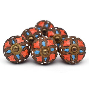 Puede incluir: Conjunto de seis pomos de armario de cerámica marrón con un diseño floral. Los pomos presentan un patrón floral azul y naranja con un centro dorado.