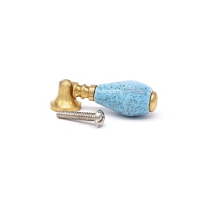 May include: A light blue ceramic cabinet knob with a brass base and a silver screw.