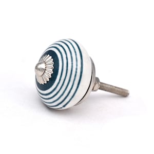 Peut inclure: Bouton de porte en céramique blanche avec un motif rayé bleu et blanc. Le bouton a une vis en métal argenté.
