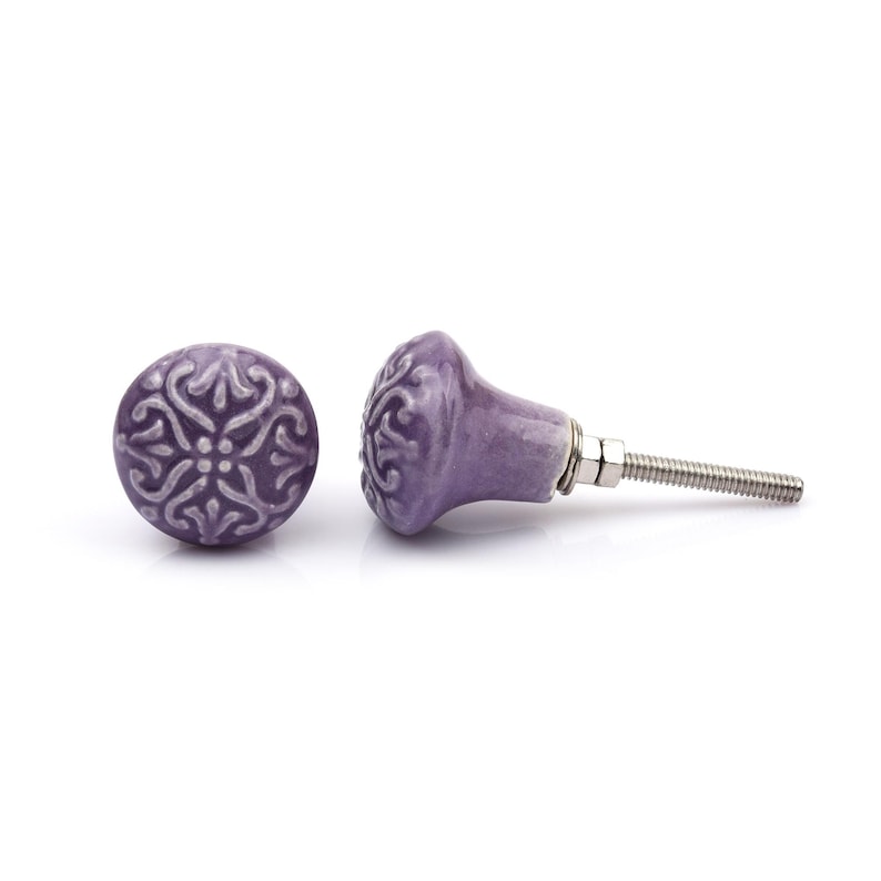 May include: A collection of twelve decorative cabinet knobs in various colours and patterns. Each knob features a round or oval shape with a metal bolt extending from the back. The designs include floral, geometric, and solid textures in shades of green, blue, orange, purple, white, and grey.