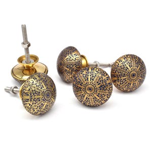 Peut inclure: Quatre boutons de porte en or avec un motif complexe bleu et or. Les boutons sont ronds et ont une vis au dos.