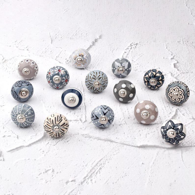 Assorted ceramic cabinet knobs, handpainted in blue, gray, and white with mandala and floral patterns for cabinet hardware.
