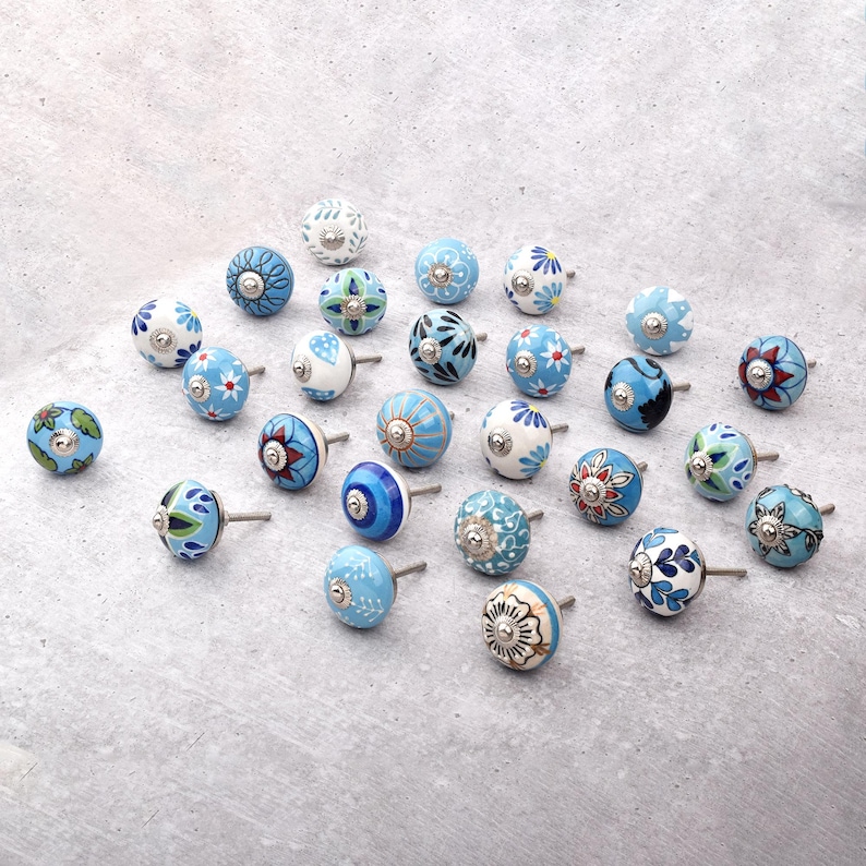 Assorted hand-painted ceramic knobs with blue and turquoise floral motifs for kitchen décor and knob cupboards.