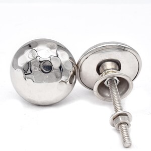 May include: Two silver hammered metal cabinet knobs with a screw and nut for installation.