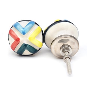 May include: Two ceramic cabinet knobs with a white base and colorful geometric designs. One knob is shown from the top and the other is shown from the side with a silver screw.