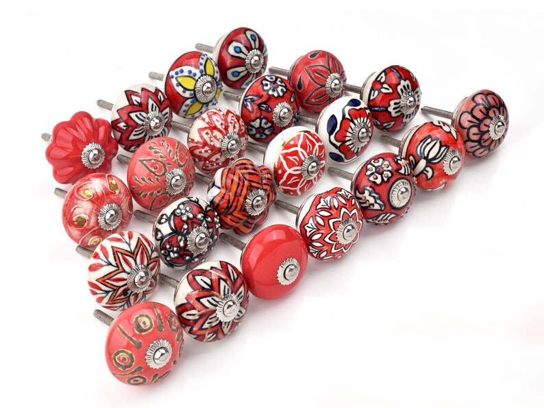 Red ceramic knobs with hand-painted white floral and mandala designs; assorted cabinet knobs for furniture and home décor.