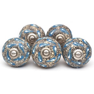 Puede incluir: Seis pomos de armario de cerámica con un patrón moteado azul y gris y detalles plateados.