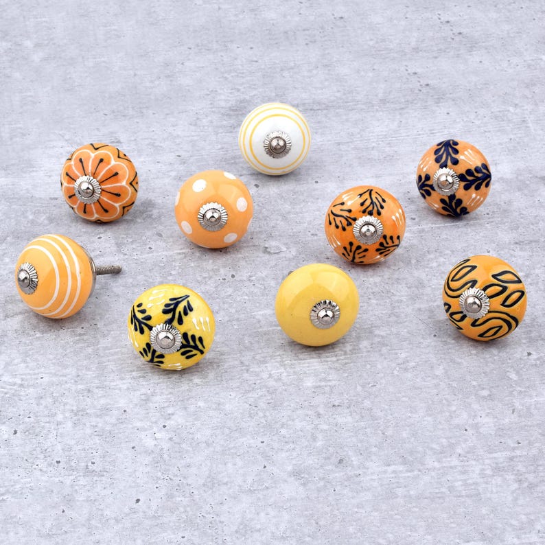 Hand-painted ceramic round knobs in yellow and orange with floral; dresser knobs and cabinet pulls for furniture hardware.