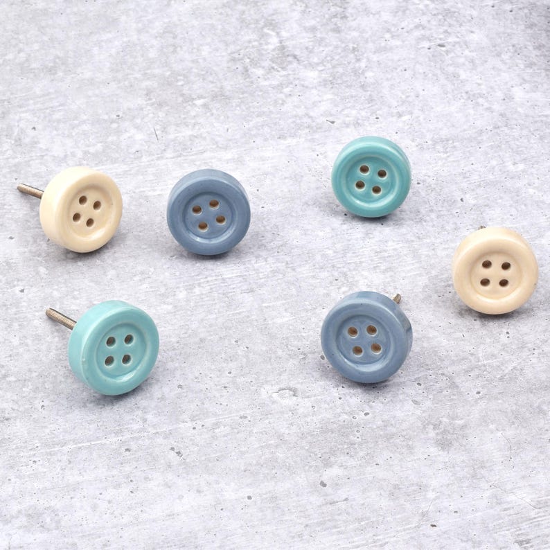 Hand-painted ceramic button knobs in cream, blue, turquoise; bold color cabinet hardware to match nursery decor.